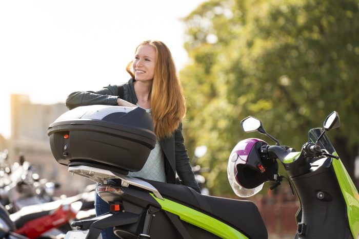 Red-haired woman on her motorcycle in a parking lot talking on smartphone