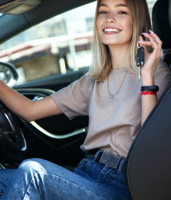 Happy smile girl in a new car with keys in her hand.